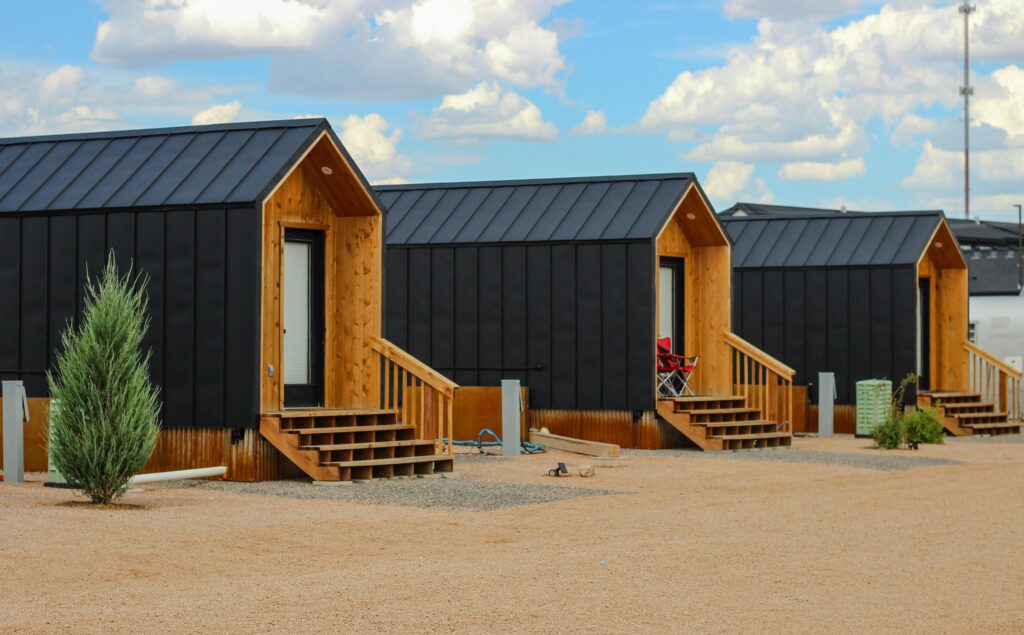 pexels photo 20513335 20513335 Row of modern black tiny houses in a desert setting under a cloudy sky.